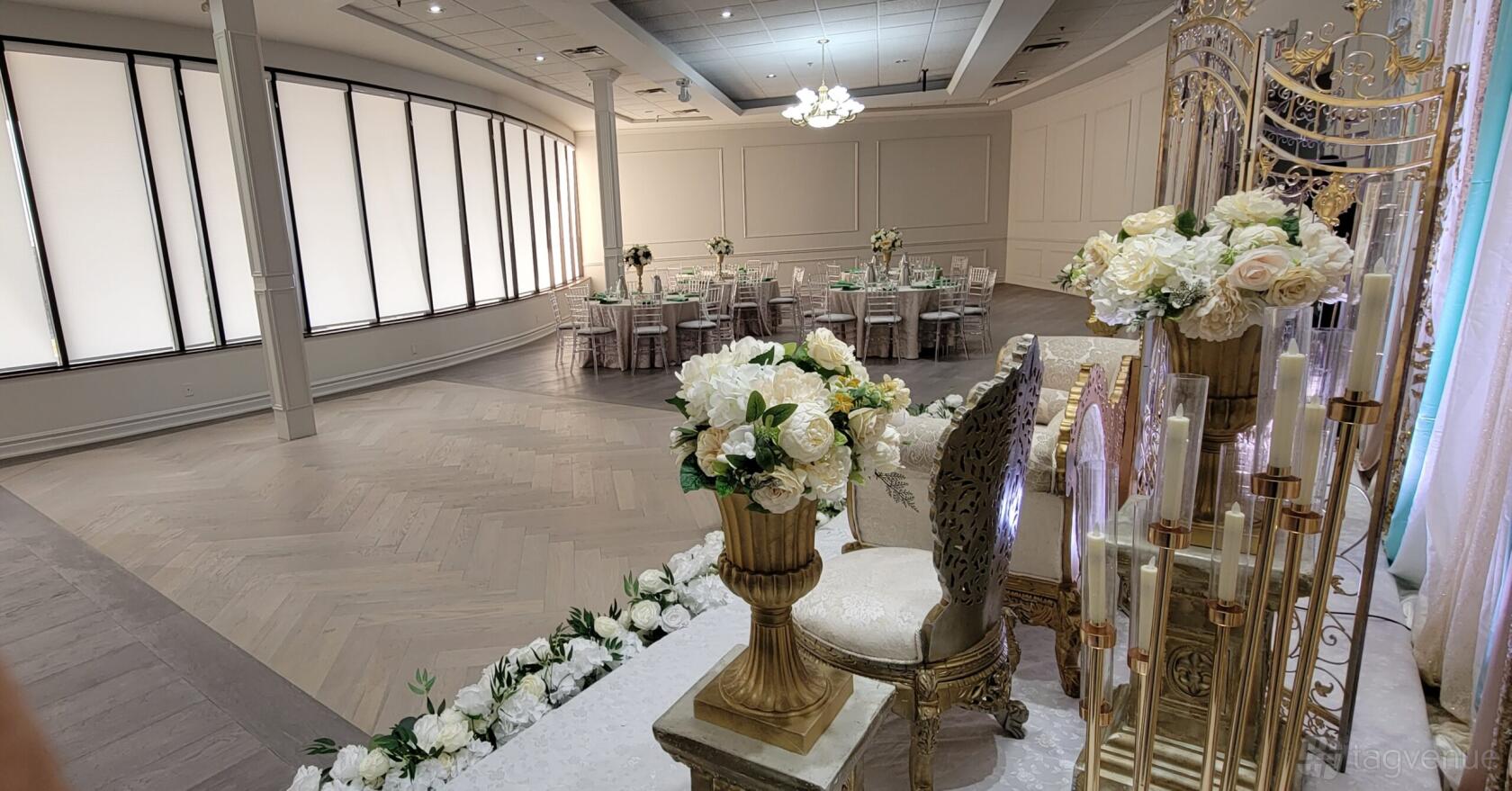 An event venue with round tables, white linens, gold chairs, and floral arrangements at Palacio Event Center.