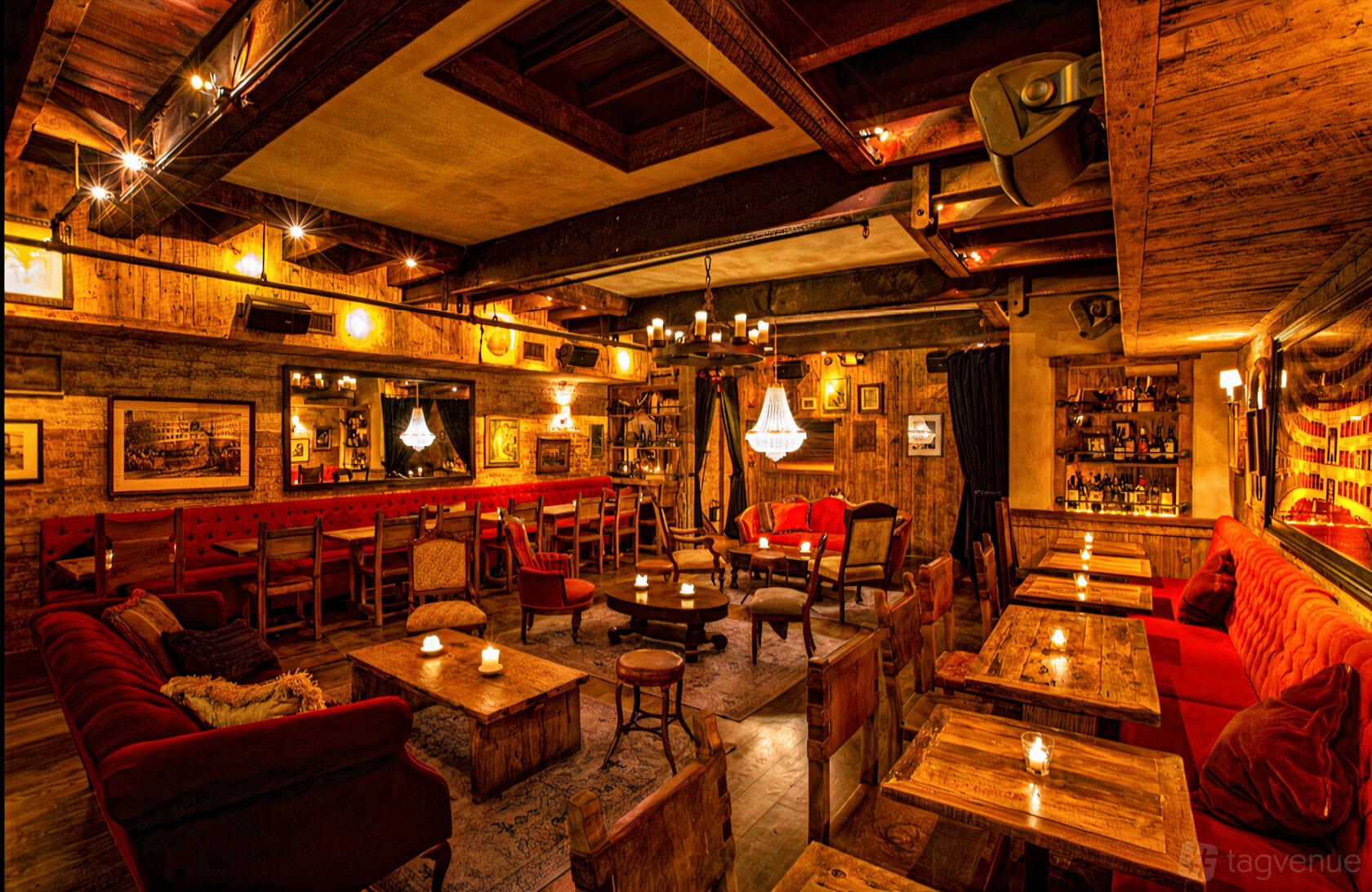 A restaurant lounge with wooden tables, velvet couches, chandeliers, and candlelit ambiance at Carroll Place.