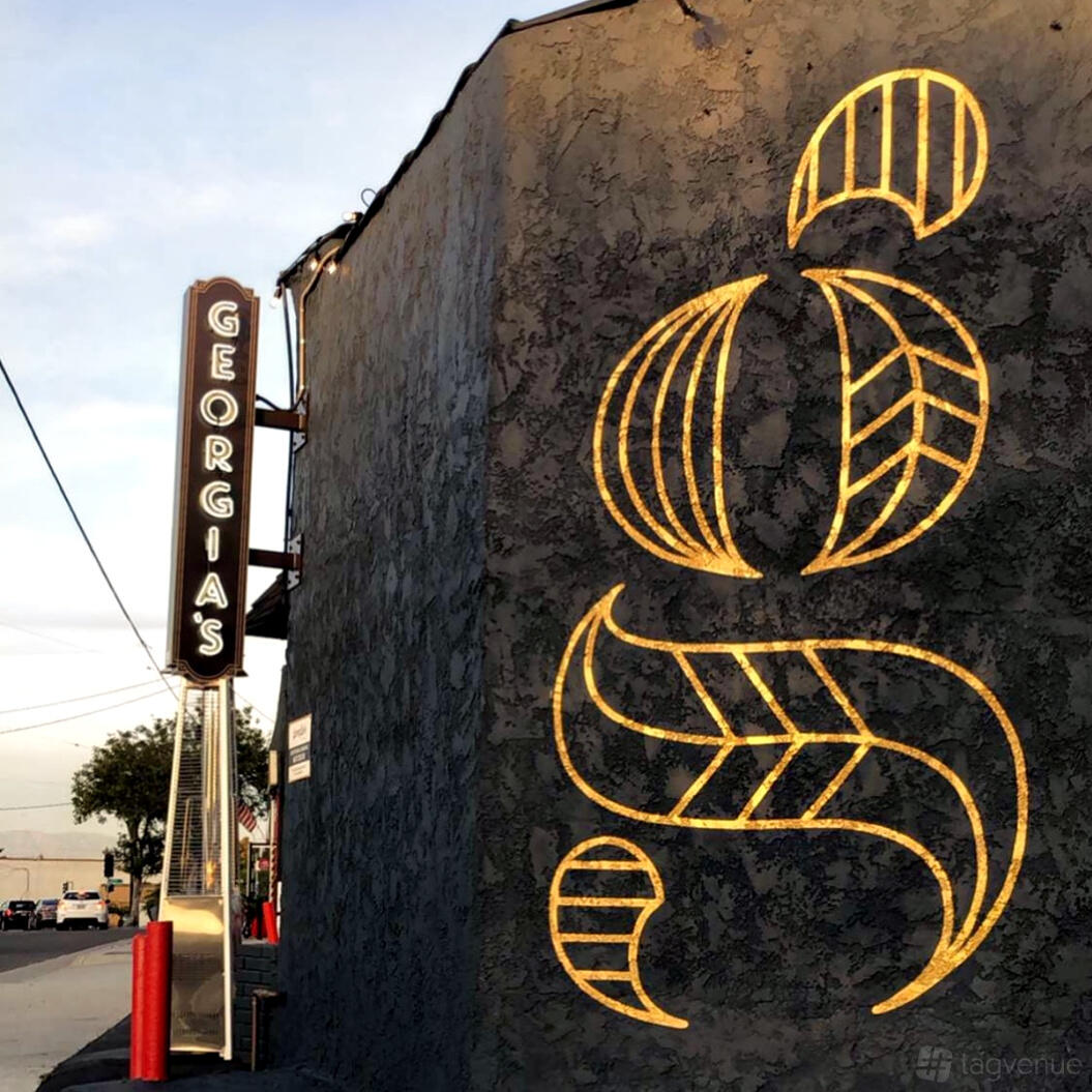 A bar exterior with a large illuminated sign reading Georgia's and decorative gold lighting on the wall at Georgia's Lounge.