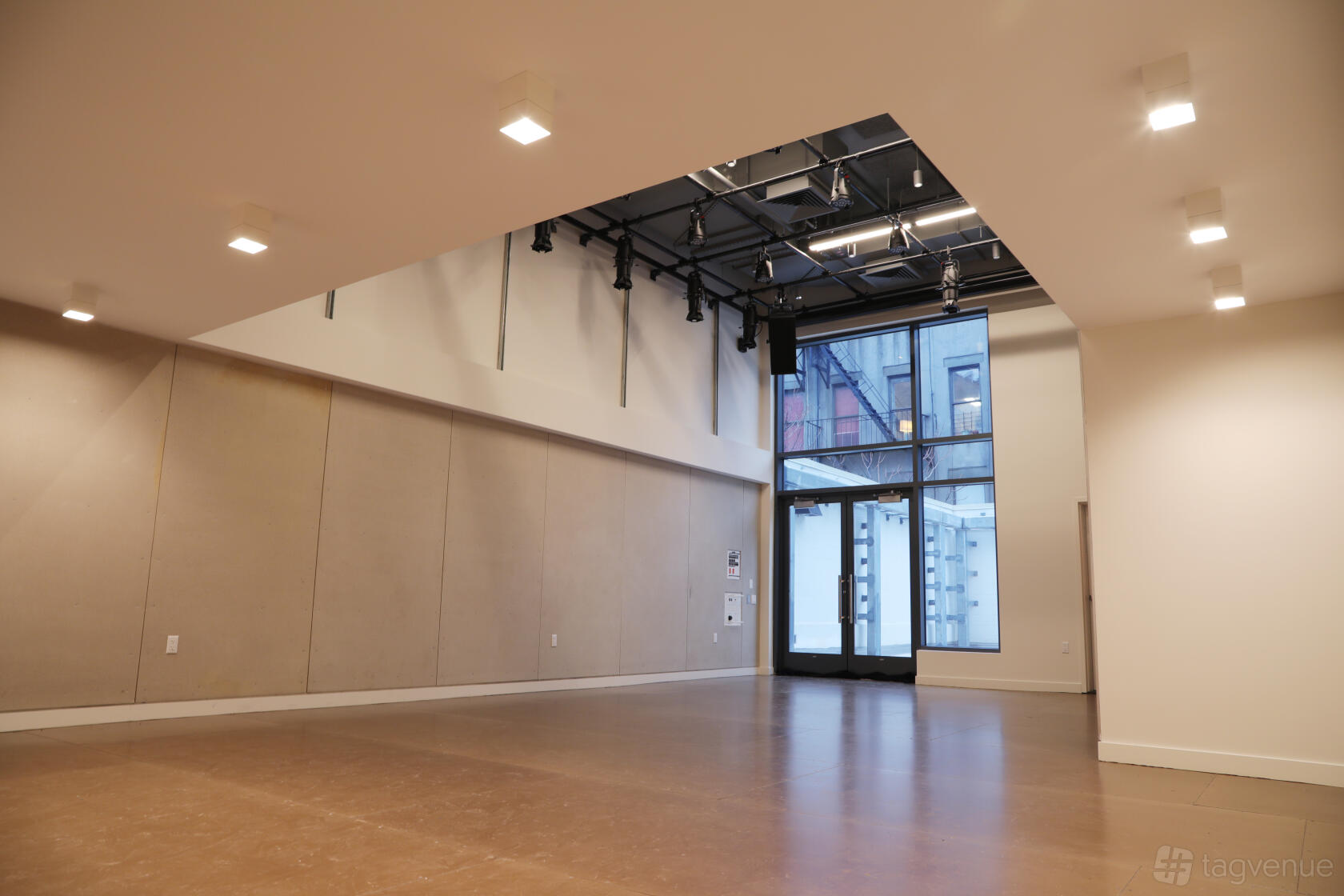 A theatre with high ceilings, track lighting, and large floor-to-ceiling windows at La MaMa Experimental Theatre Club.