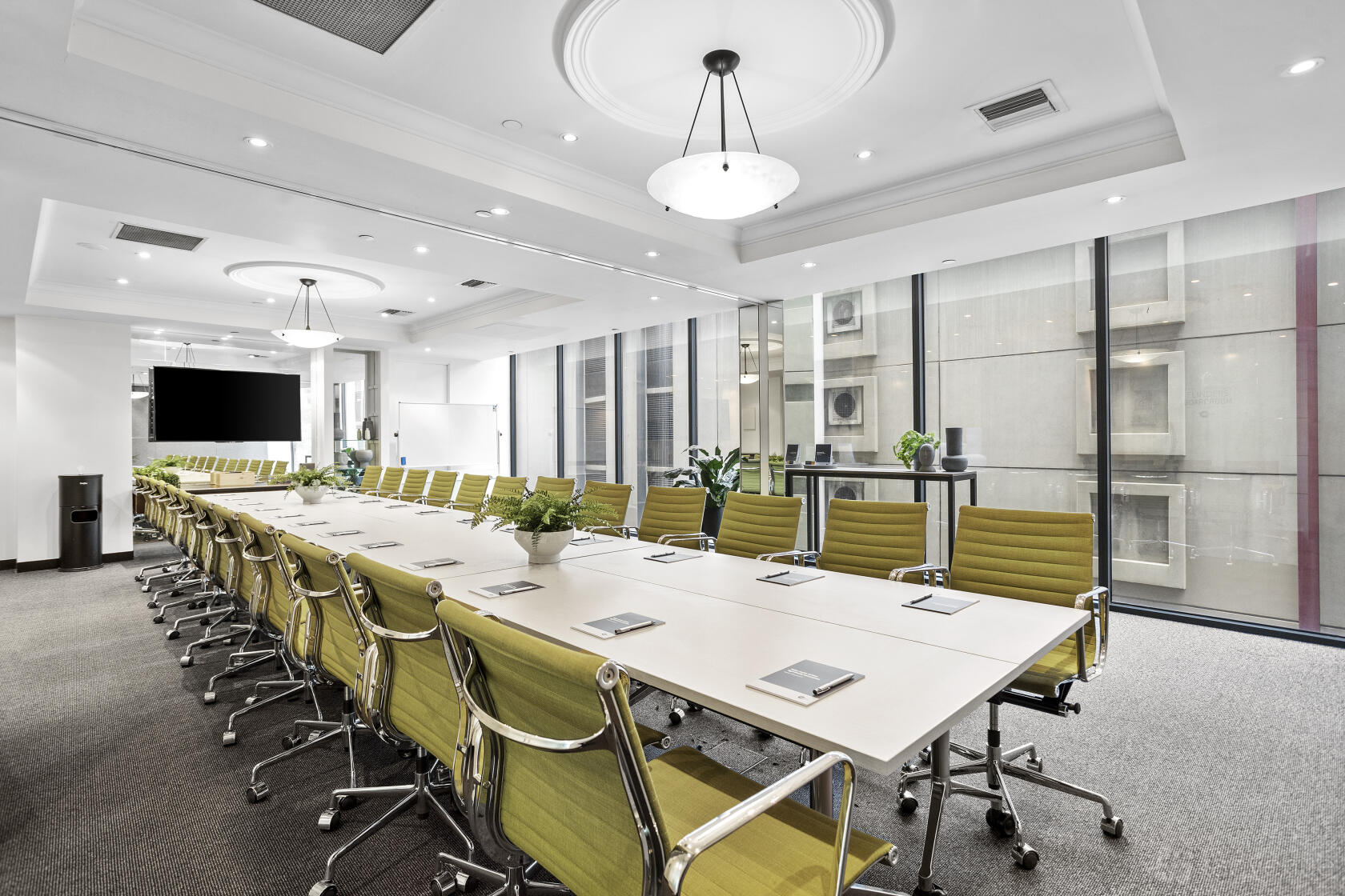 A boardroom with a long conference table, green swivel chairs, and floor-to-ceiling windows at St Kilda Rd Towers.