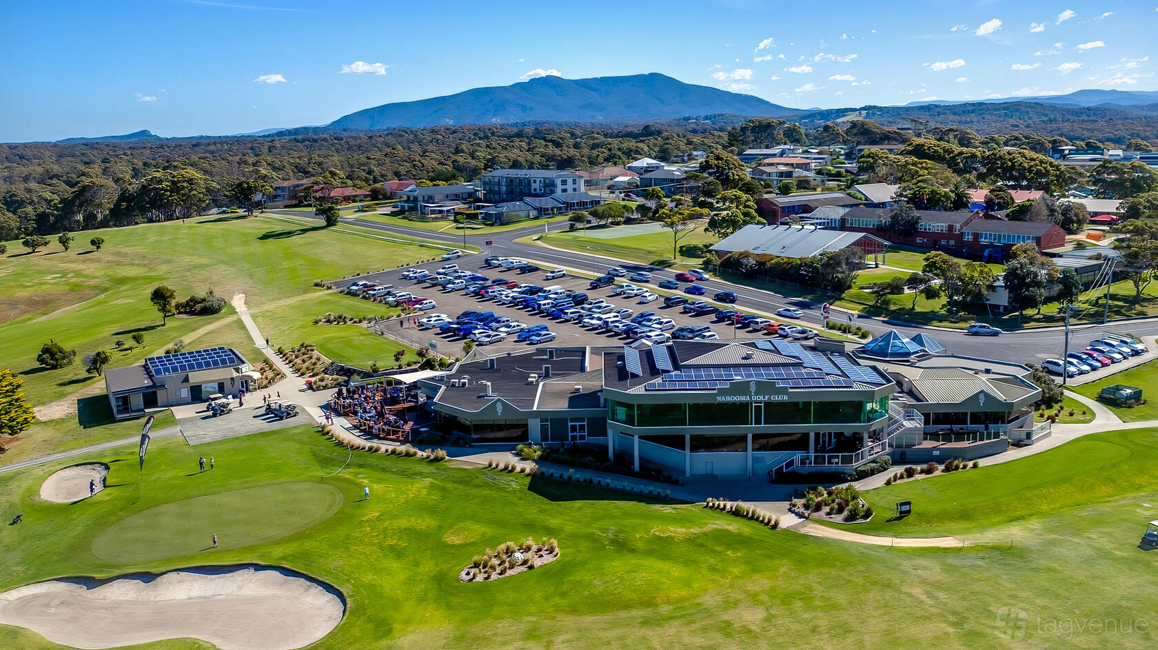 A golf club with sprawling greens, sand bunkers, clubhouse, and mountain views at Narooma Golf Club.