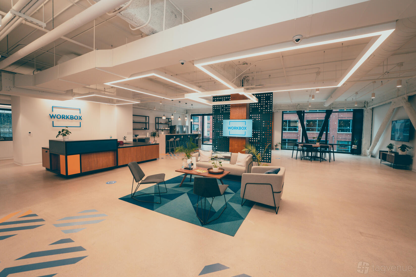 A coworking space with lounge seating, sleek lighting fixtures, and floor-to-ceiling windows at Workbox - River North.