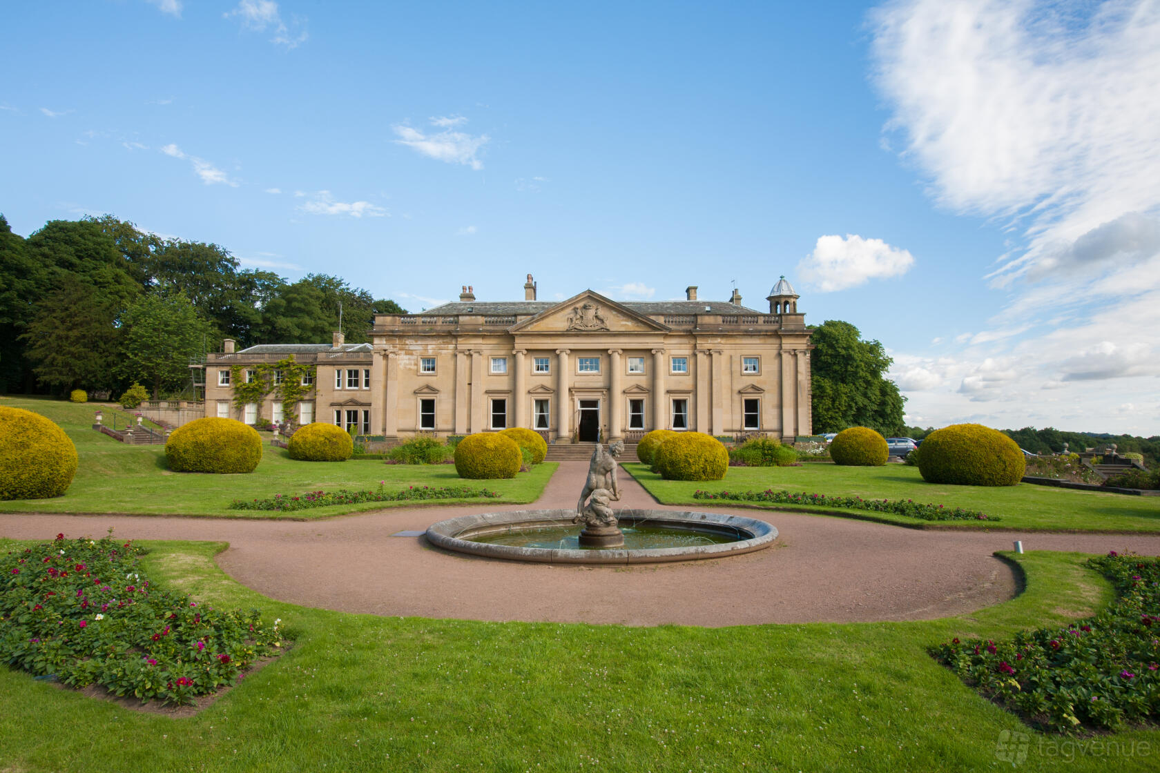 A historic building with manicured lawns, a central fountain, and neoclassical architecture at Wortley Hall.