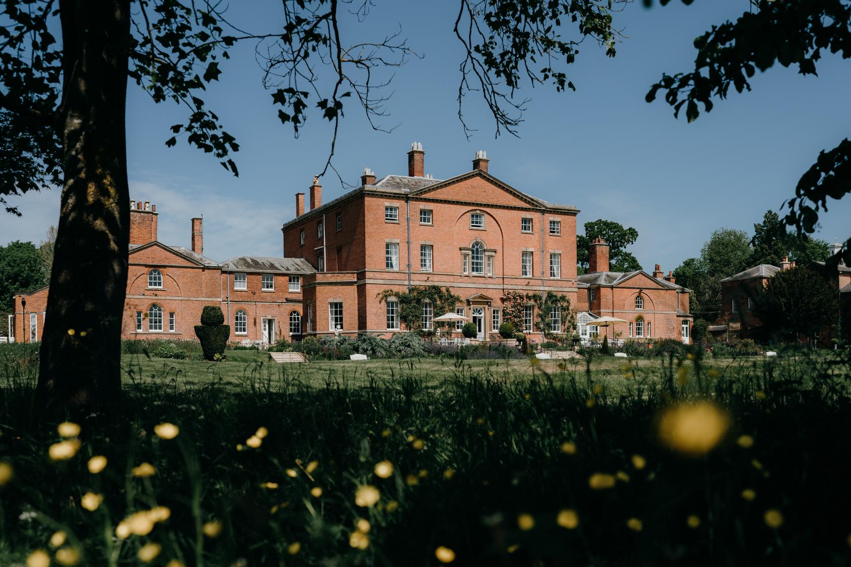 A grand brick country house with large windows and landscaped gardens at Norwood Park Country House.