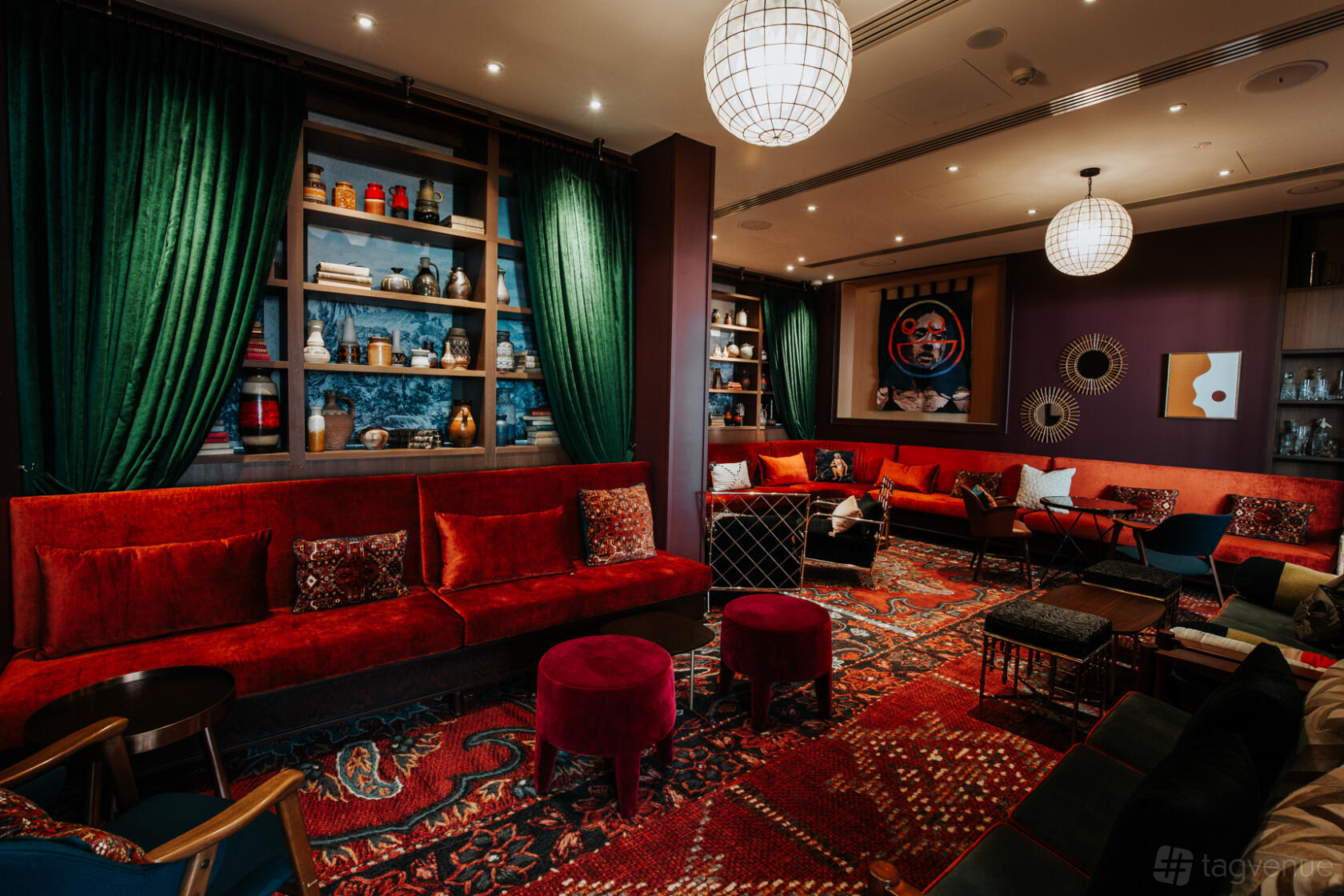 A function room with velvet sofas, patterned rugs, and built-in bookshelves at Ovolo The Valley.