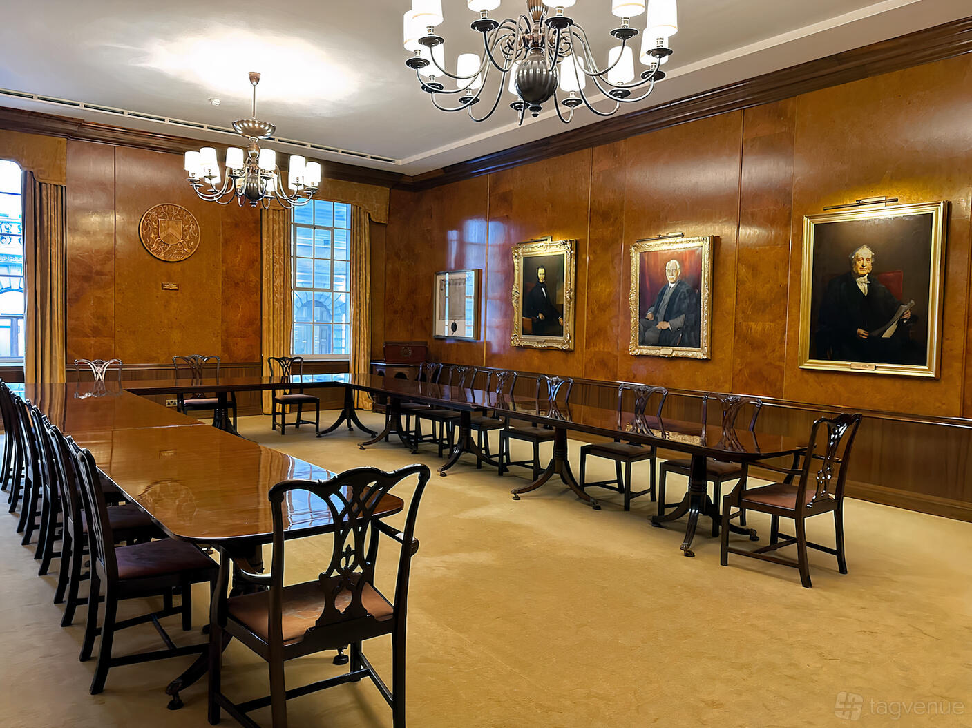 A historic hall with polished wood-paneled walls, large rectangular meeting table, and framed portraits at Carpenters' Hall.