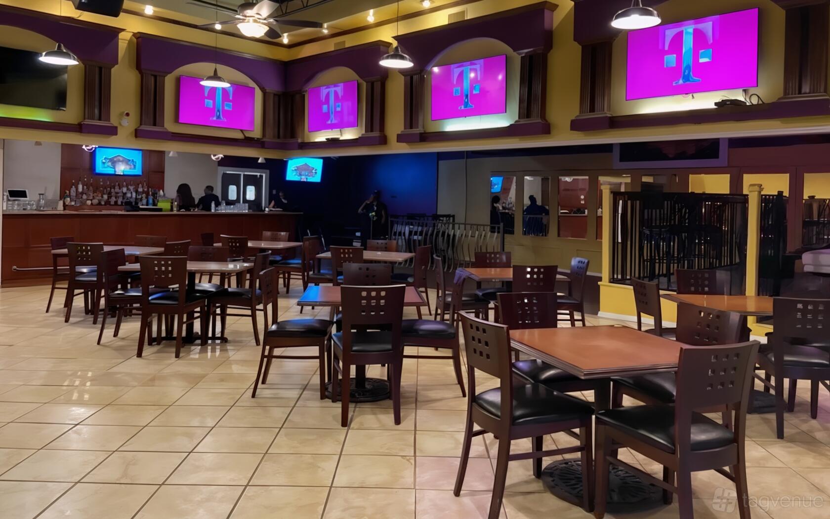 A bar with tiled floors, square wooden tables, contemporary chairs, and multiple screens at 1540 Bar & Grill.