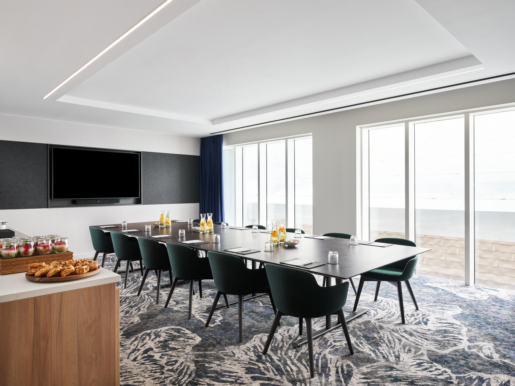 A boardroom with floor-to-ceiling windows, a large conference table, and refreshments at Hyatt Regency London Stratford.