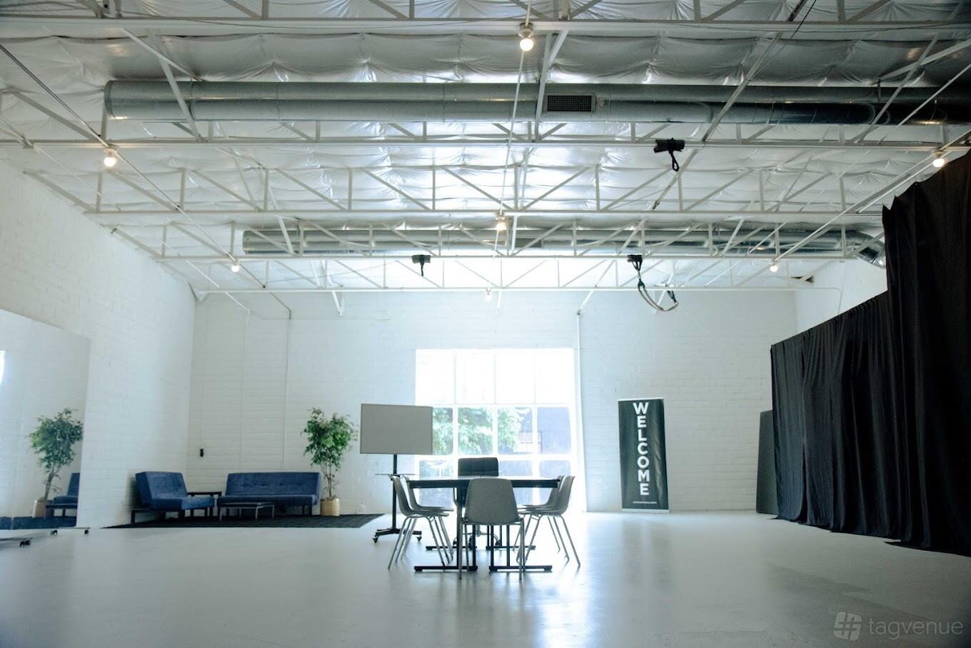 An event venue with high ceilings, white walls, skylights, and a seating area with sofas and chairs at Soar Too.