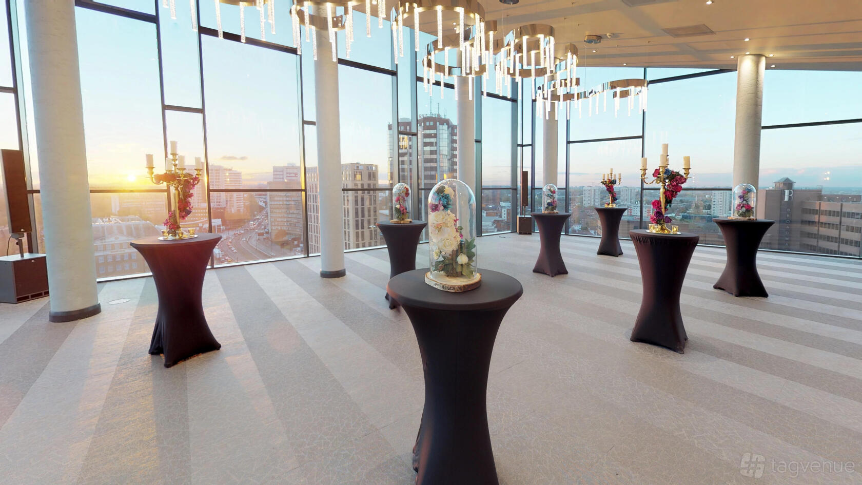 An event space with floor-to-ceiling windows, city skyline views, and cocktail tables with centerpieces at Park Regis Hotel Birmingham Sky Loft.