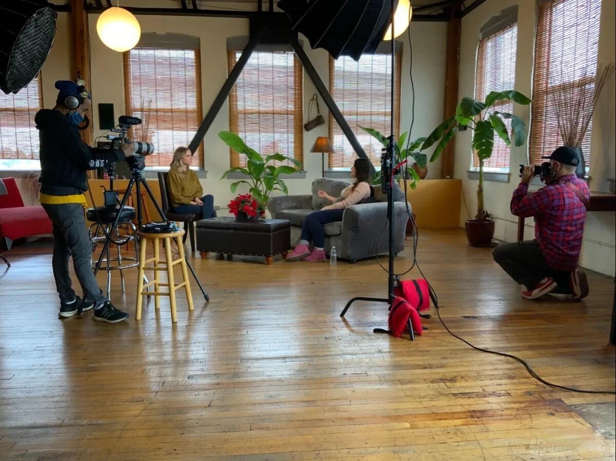 An event venue with hardwood floors, large windows with bamboo shades, and lounge seating at MyGroove Design, Inc.