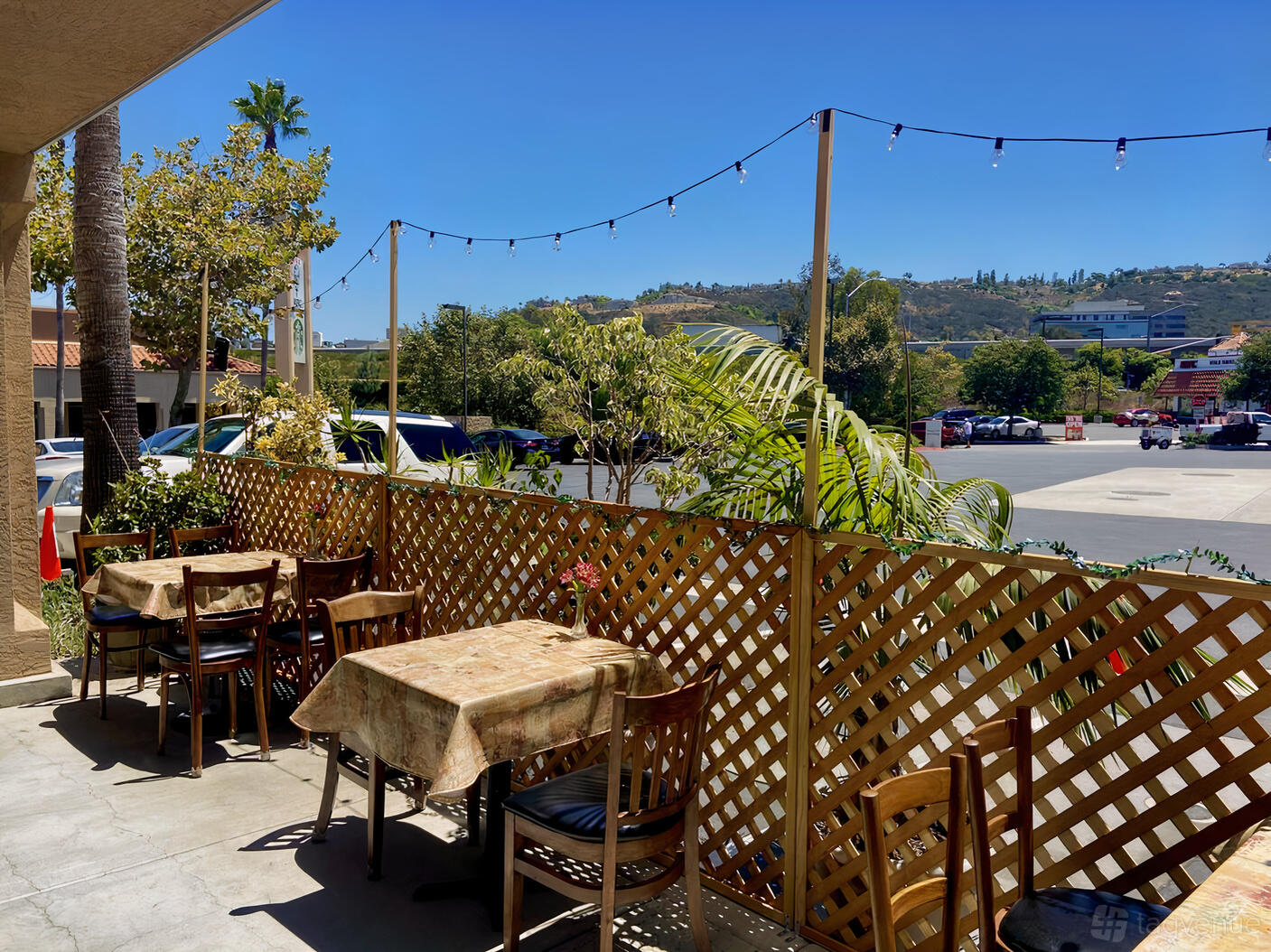An outdoor patio with wooden lattice fencing, string lights, and tables with floral tablecloths at Pernicano's Ristorante.
