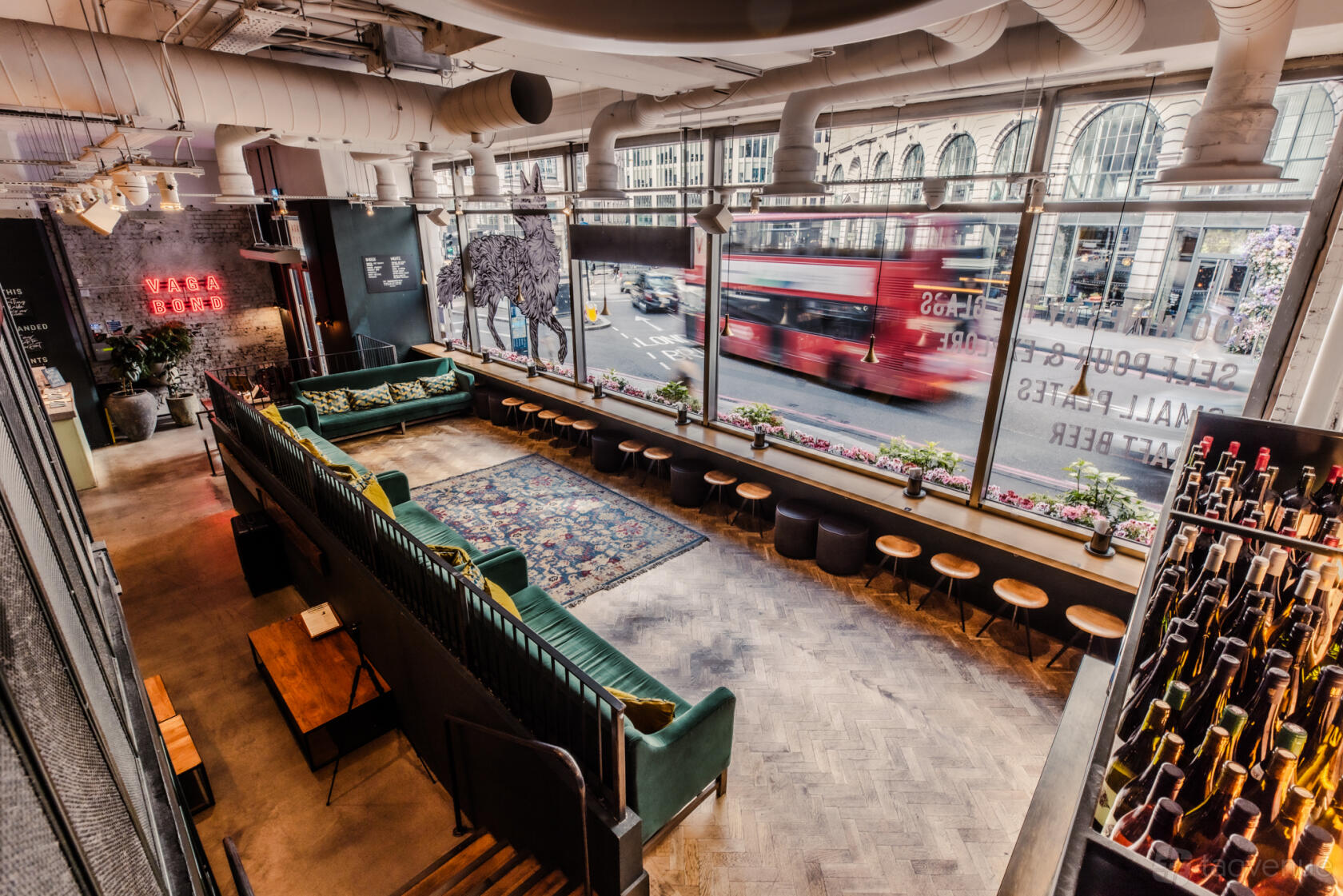 An event space in a bar with floor-to-ceiling windows, velvet sofas, and a patterned rug at Vagabond Monument.