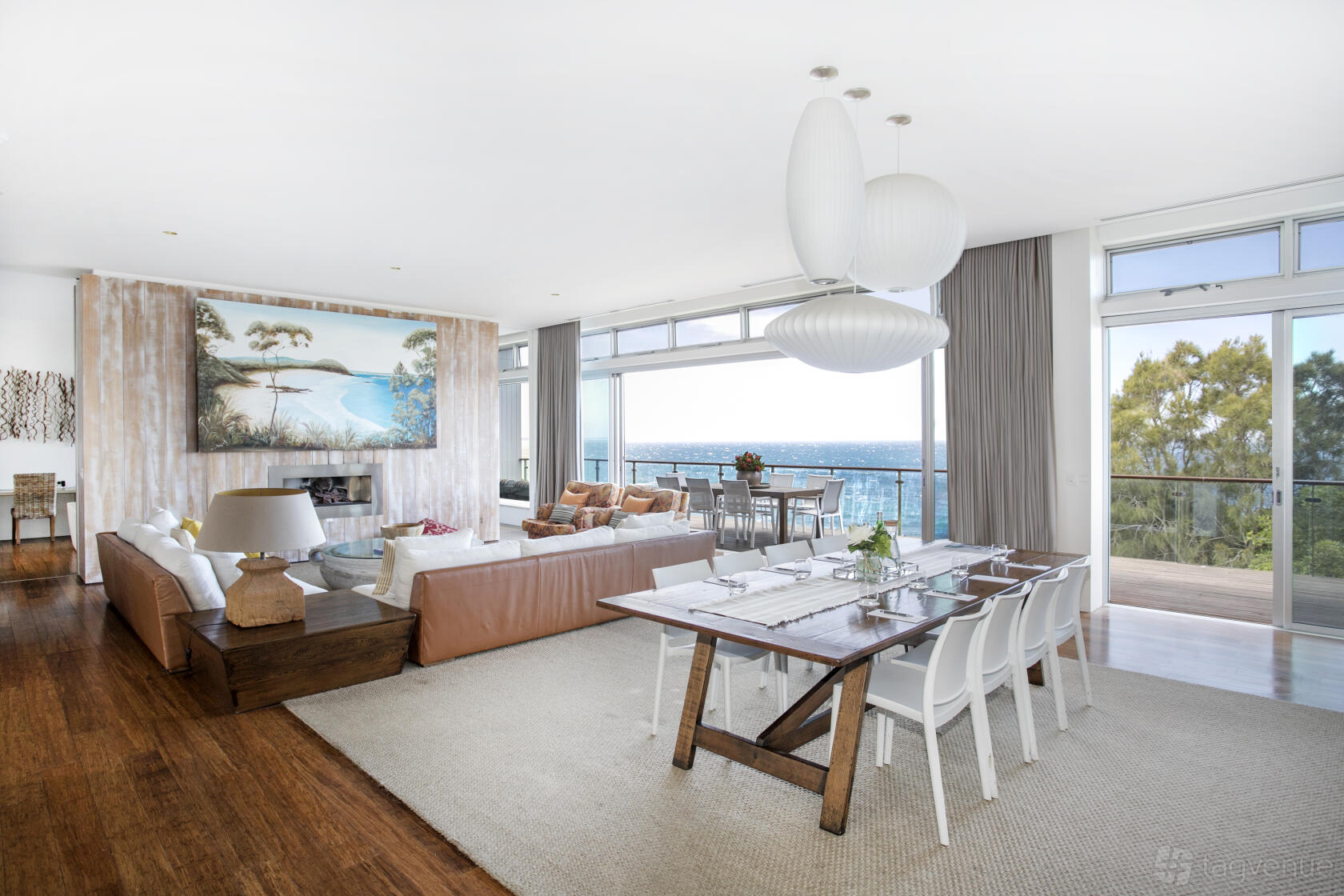 An event space in a hotel with floor-to-ceiling windows, a wooden dining table, and ocean views at Bannisters by the Sea.