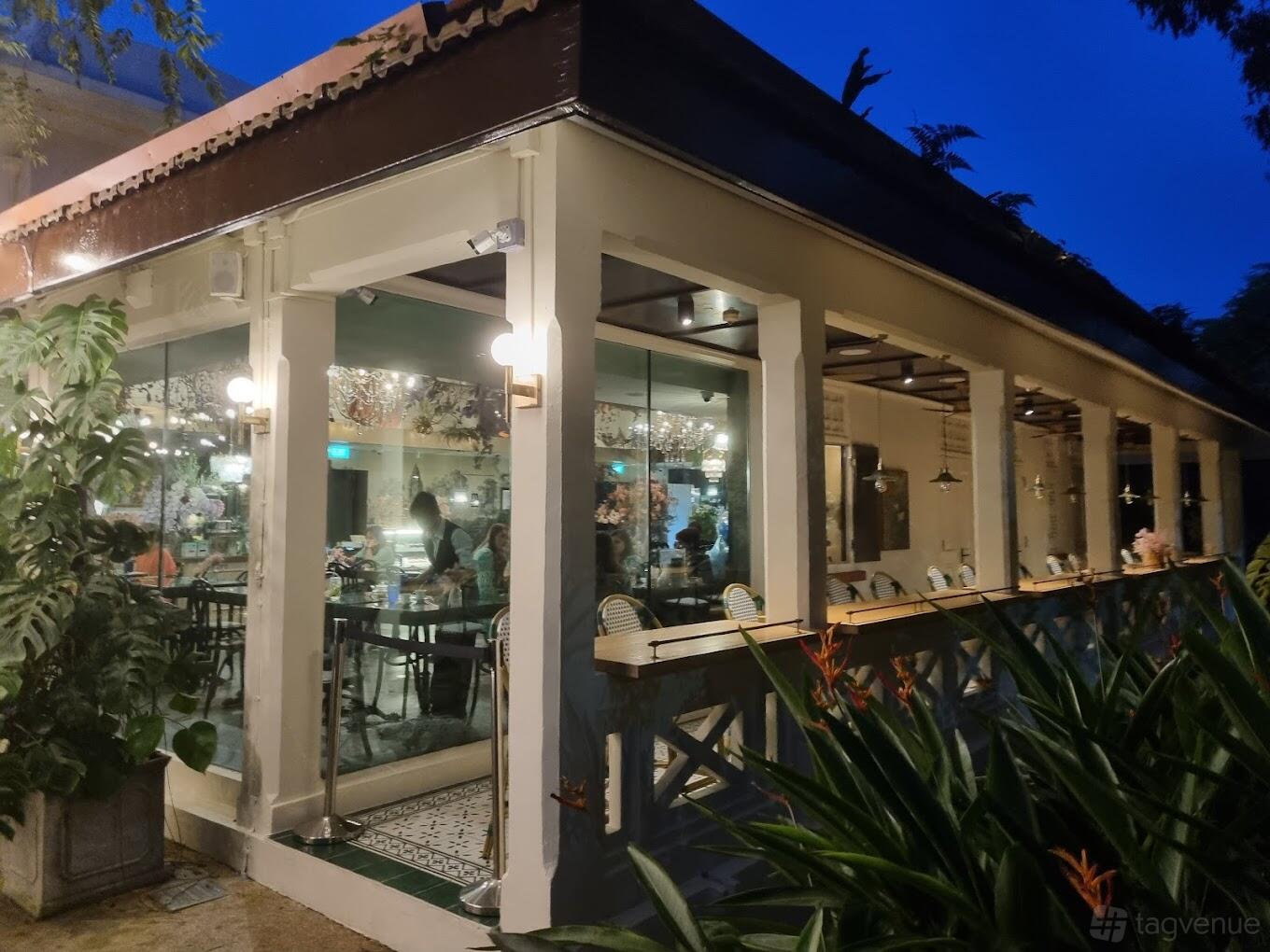 A restaurant with glass walls, indoor seating, and surrounding greenery at Le Jardin.