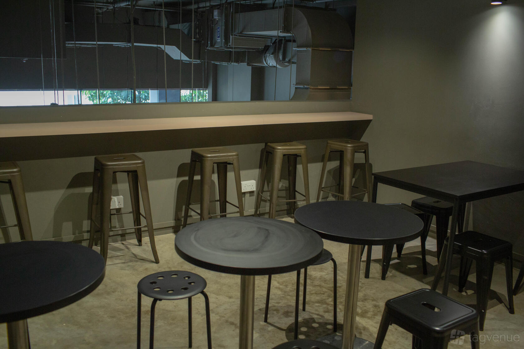 An event space in a cafe with round black tables, metal stools, and a high counter at State Of Affairs.