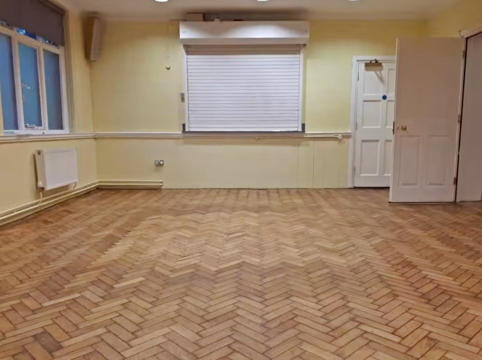 A church hall with herringbone wood flooring, yellow walls, and a service counter at St Paul's UR Church and halls Croydon.