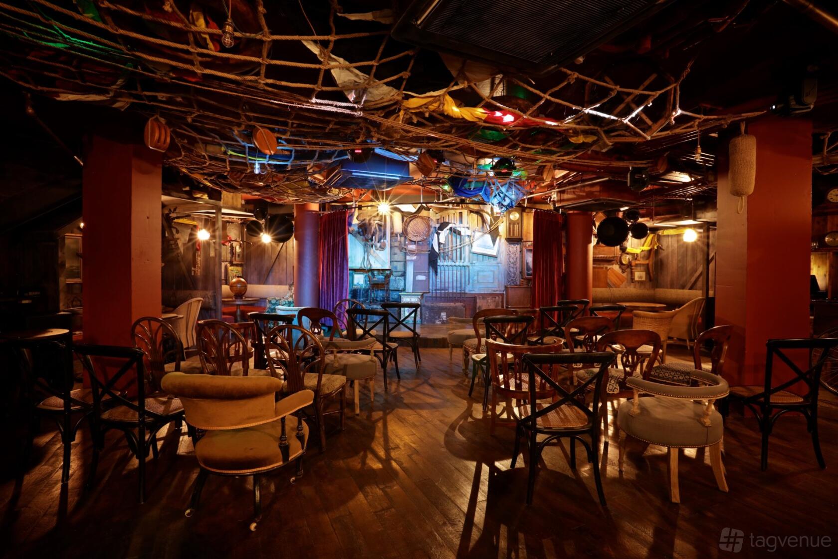 A dining room in a cocktail bar with eclectic chairs, hanging ropes, and stage lighting at Mr Fogg's City Tavern.
