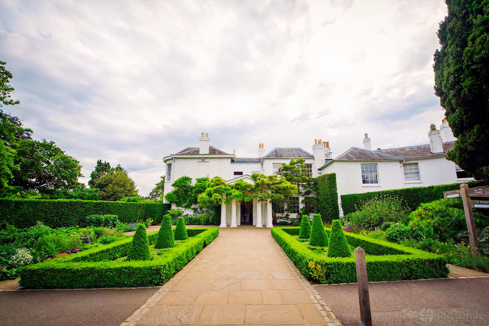 A white historic building with manicured gardens and a stone walkway at Pembroke Lodge.