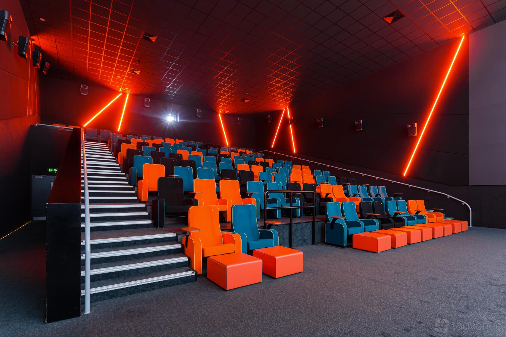A screening room with tiered rows of orange and blue recliner seats and neon wall lights at The Light Stockport.