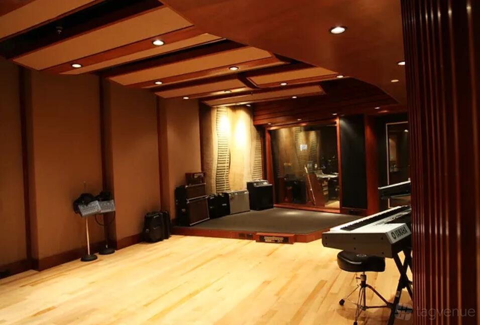 A recording studio with a piano keyboard, amplifiers, wood floors, and acoustic panels at Dream Recording Studios.