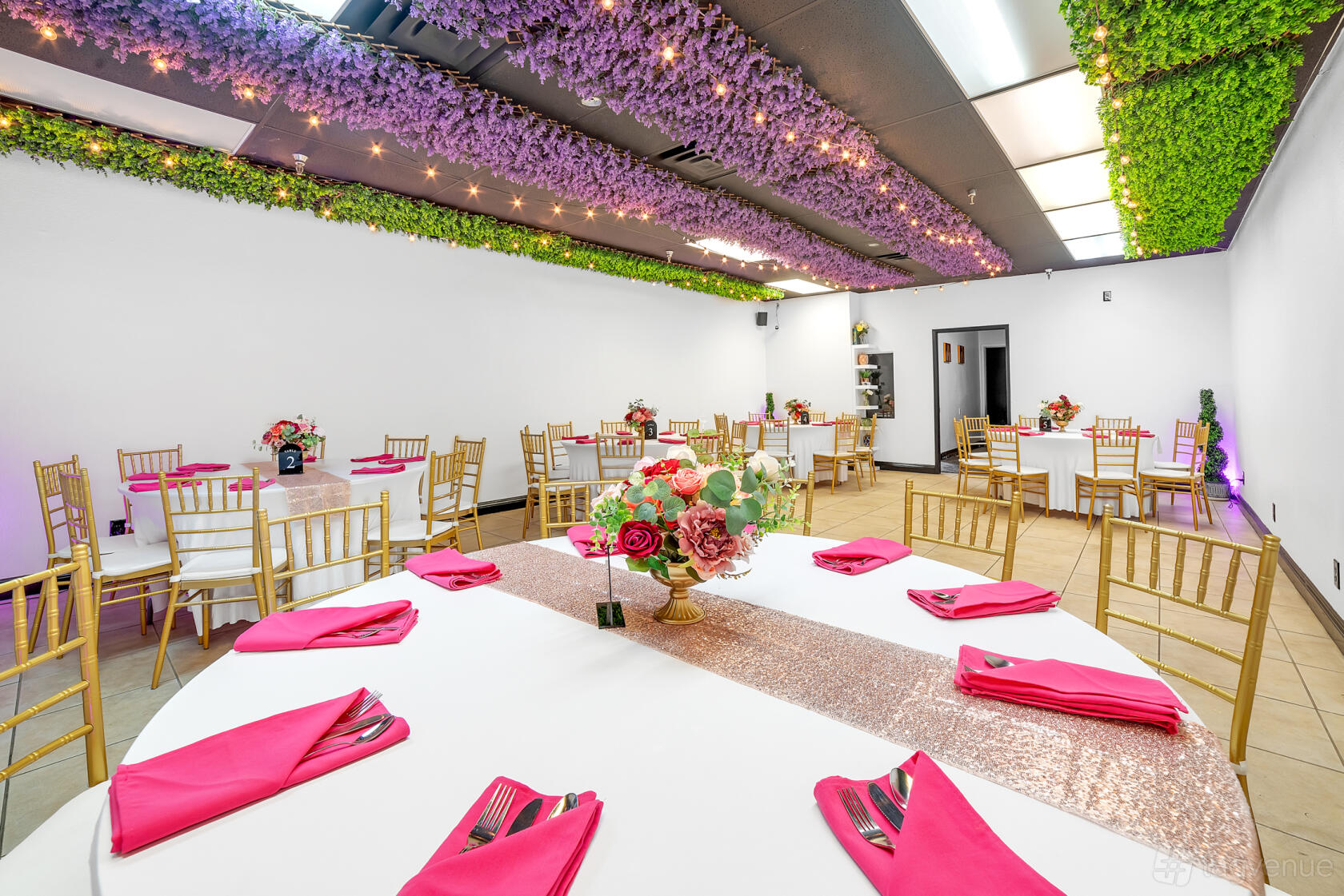 A function room with floral ceiling decor, round tables with white linens, and gold chairs at Icebox LV