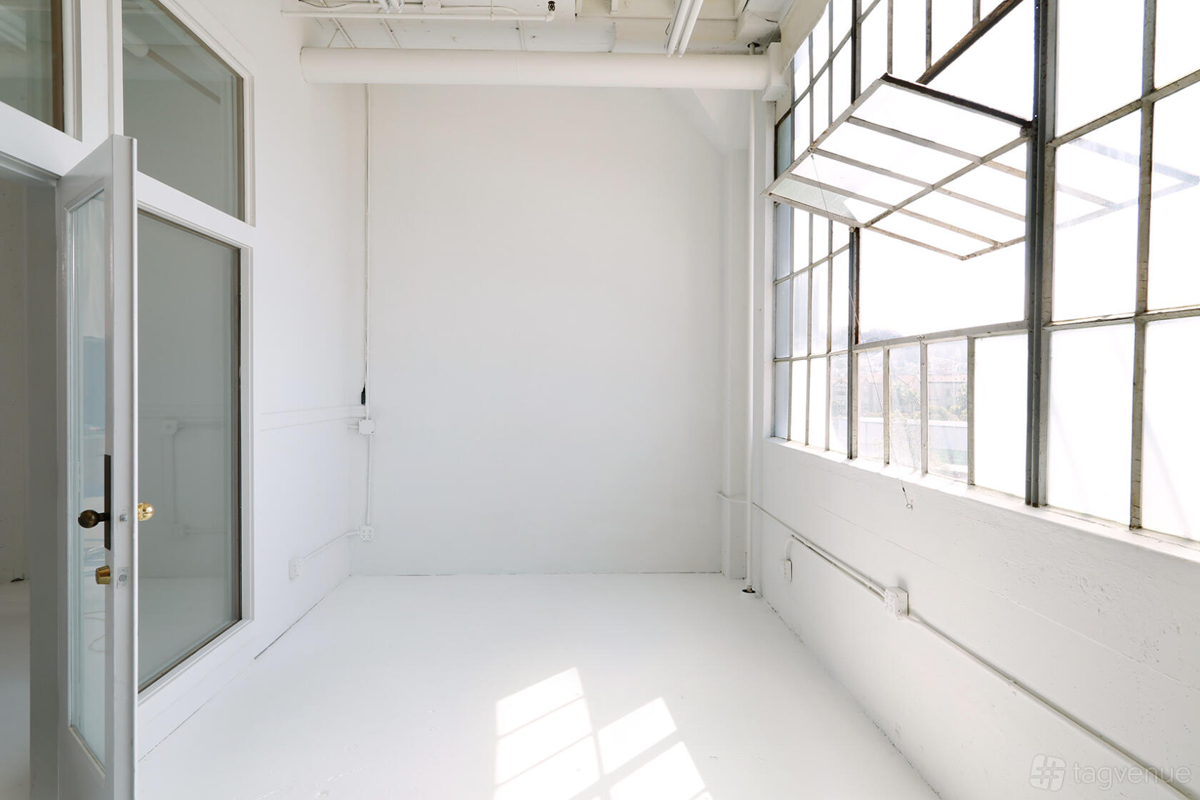A photo studio with large industrial windows, white walls, and an abundance of natural light at Burdick Studio.