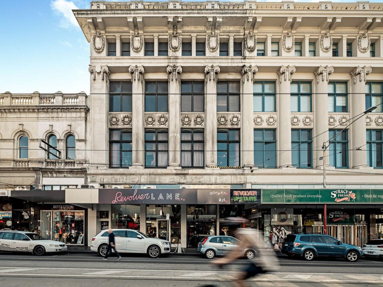 A historic building with ornate columns, decorative stonework, and large windows above street-level shops at Revolver Lane.