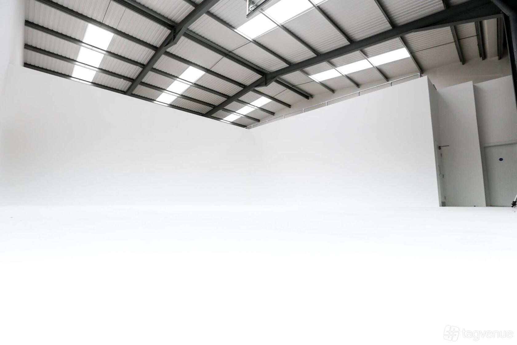A photo studio with high ceilings, a white cyclorama wall, and overhead industrial lighting at Foundry Film Studios.