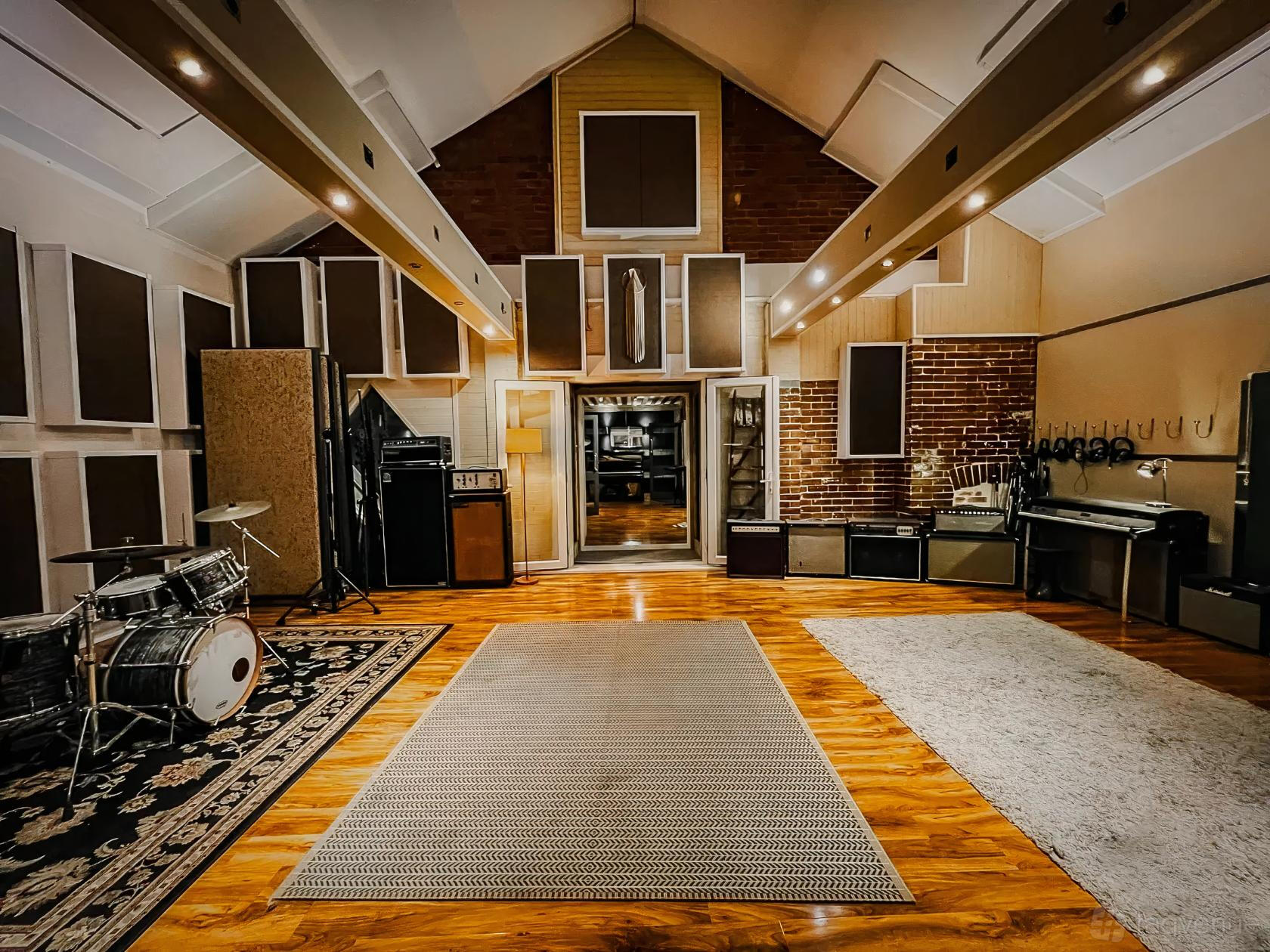 A recording studio with exposed brick walls, drum set, amps, and acoustic panels at Buffalo Studio.
