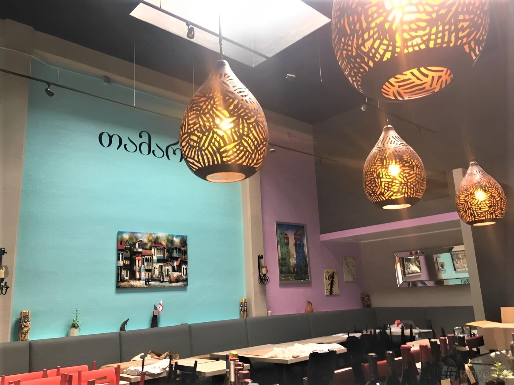 A restaurant with carved pendant lighting, colorful walls, and framed artwork at Tamari Authentic Georgian Cuisine.