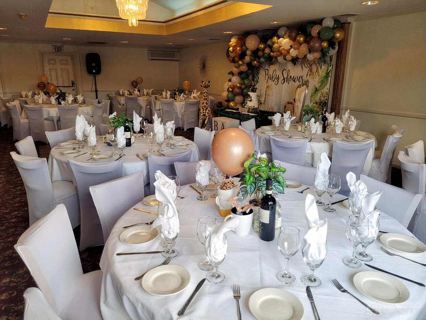 A restaurant with round tables draped in white linens, folded napkins, and balloon decorations at Tombolino Ristorante.