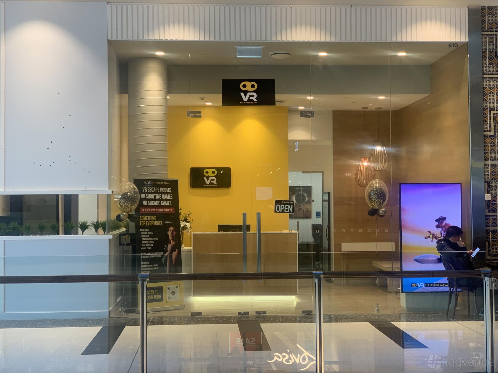 An event venue with a yellow reception desk, VR signage, and glass entry at VR Kingdom.