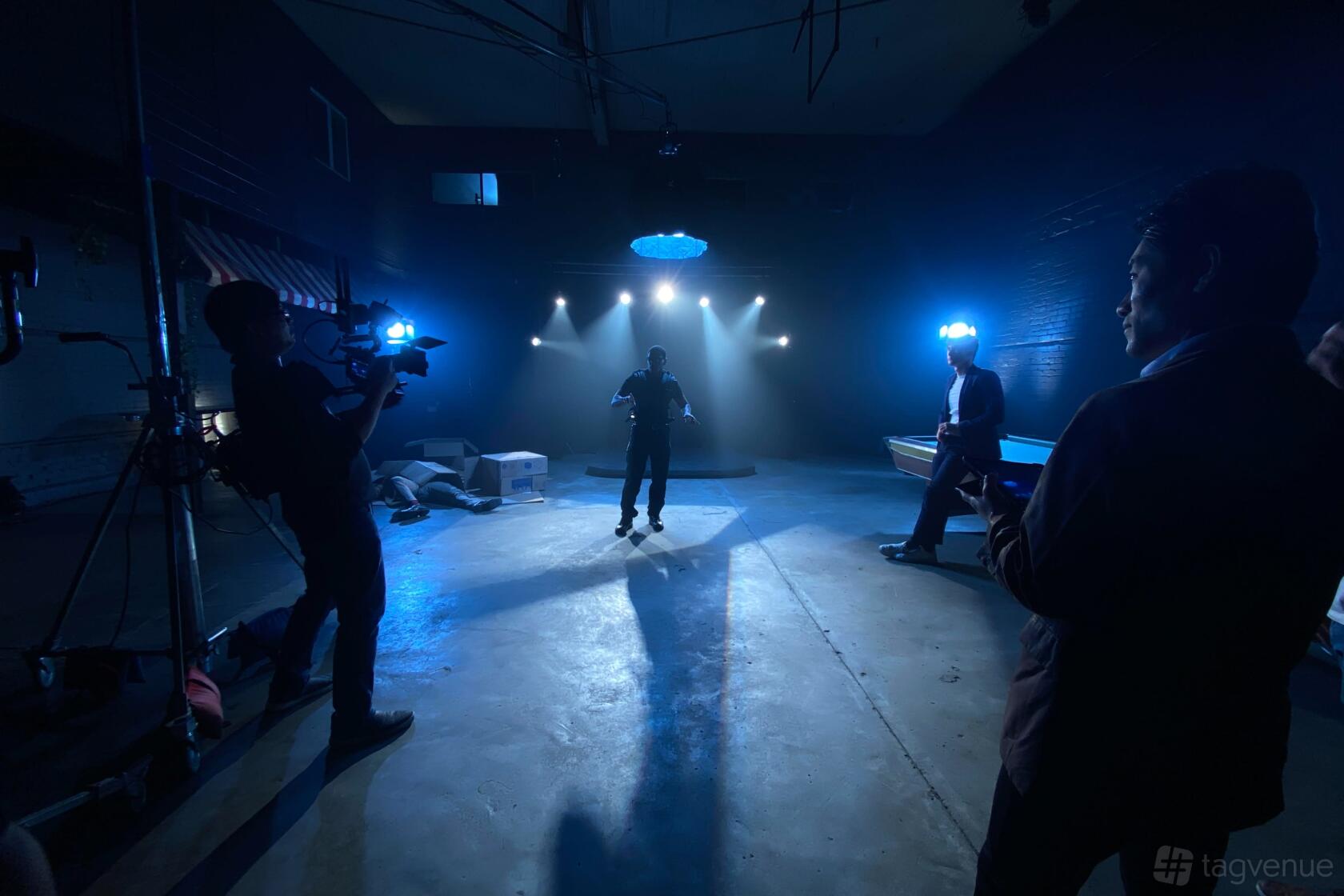 A film studio with dramatic blue stage lighting, concrete floors, and filming equipment at Film Studio With Free Lighting.