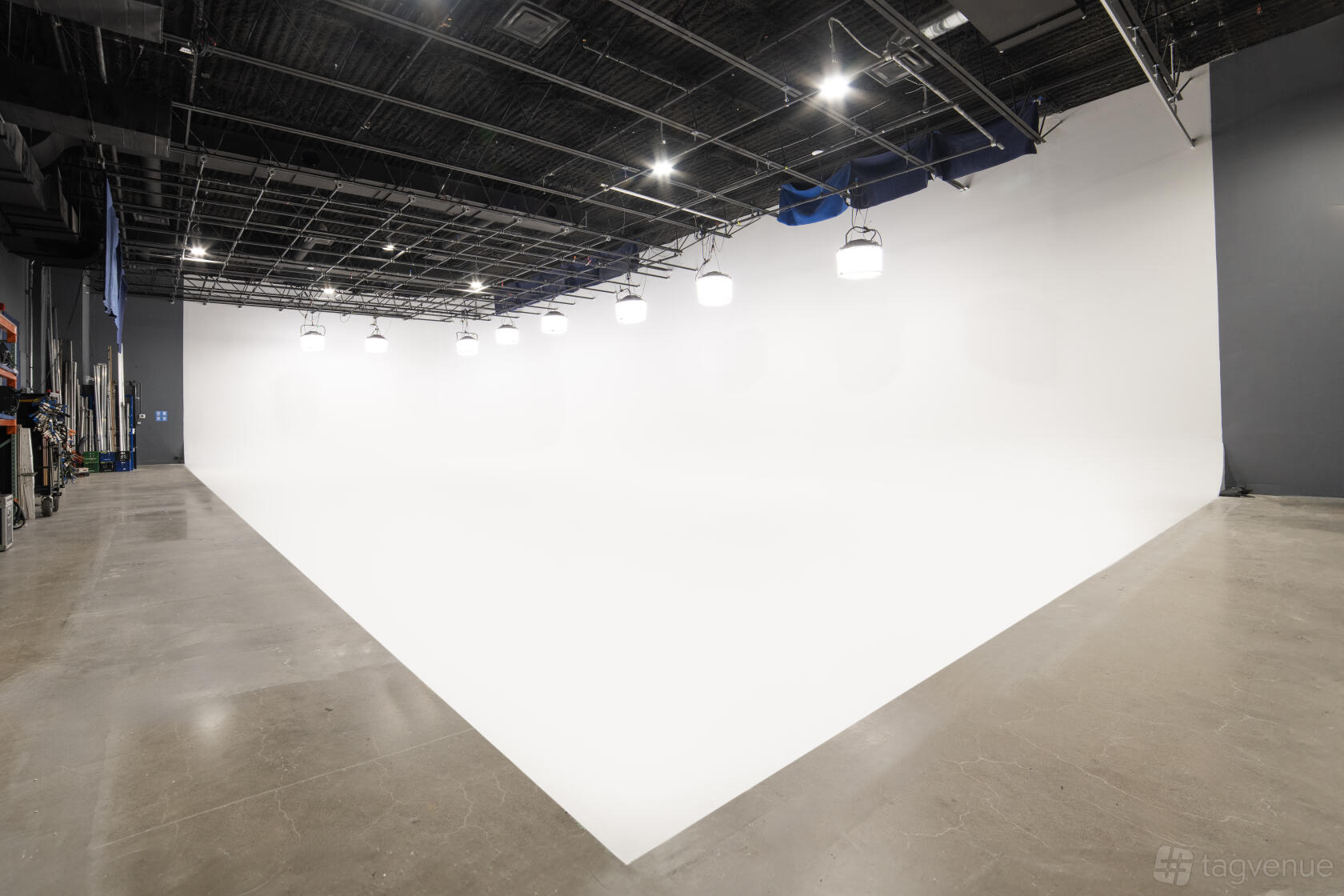 A film studio with a large white cyclorama wall, polished concrete floor, and overhead lighting at AstroLab.