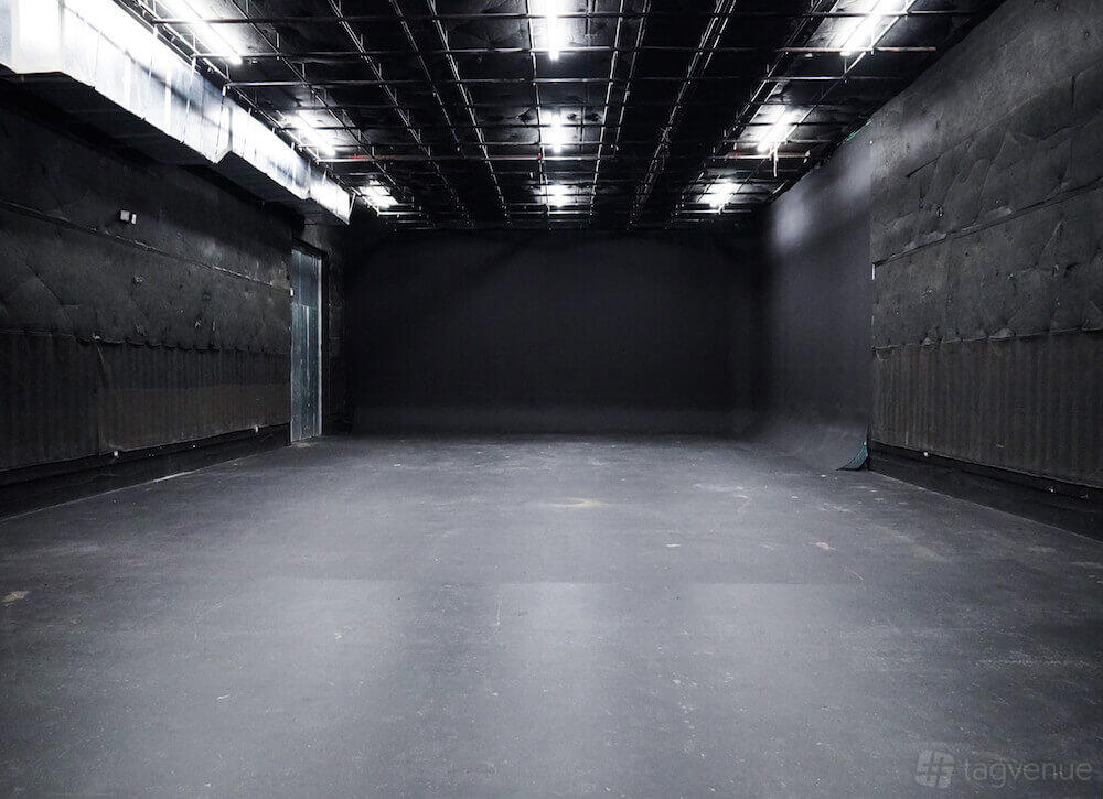 A photo studio with blacked-out walls, exposed ceiling grid, and seamless flooring at M3 Studios.