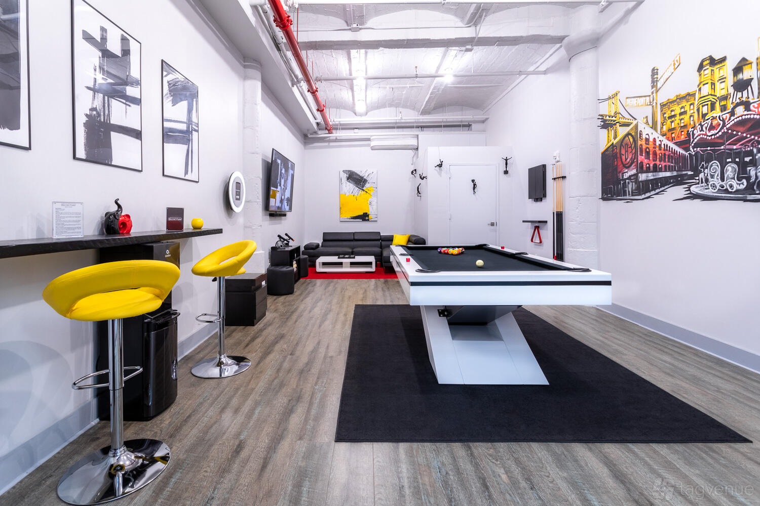 An event venue with a pool table, wall art, yellow bar stools, and lounge seating at Social Cues - The Gallery.