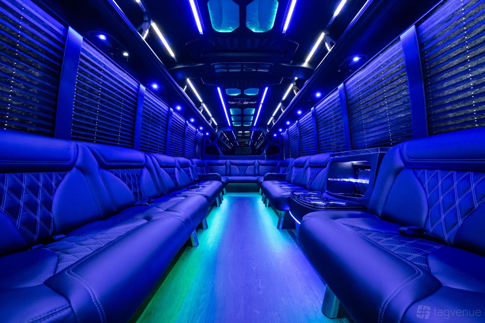 A party bus with blue LED lighting, black leather seating along both sides, and wood flooring at Party Bus LA.