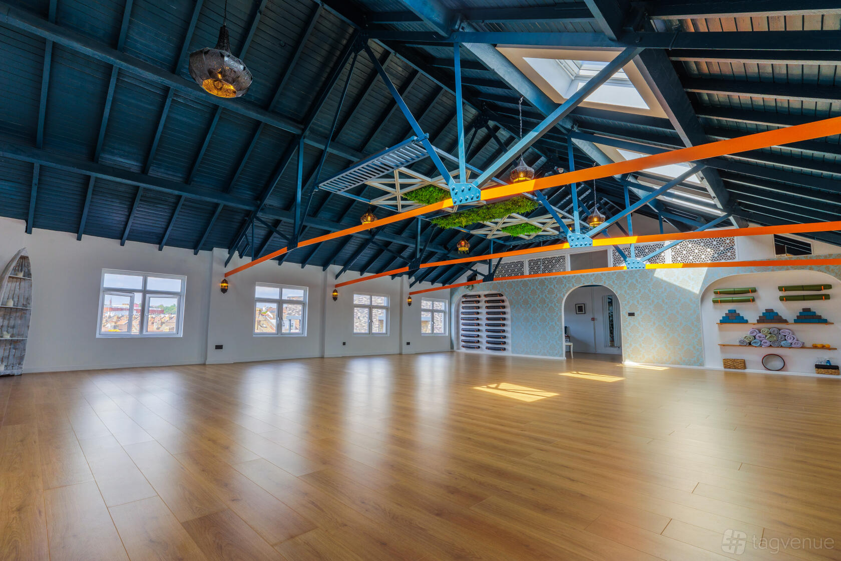 An event venue with exposed blue beams, skylights, and wood floors at Highvibe Studio.