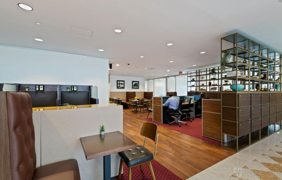A coworking space with wood floors, partitioned desks, and open shelving at Servcorp - Williams Tower.