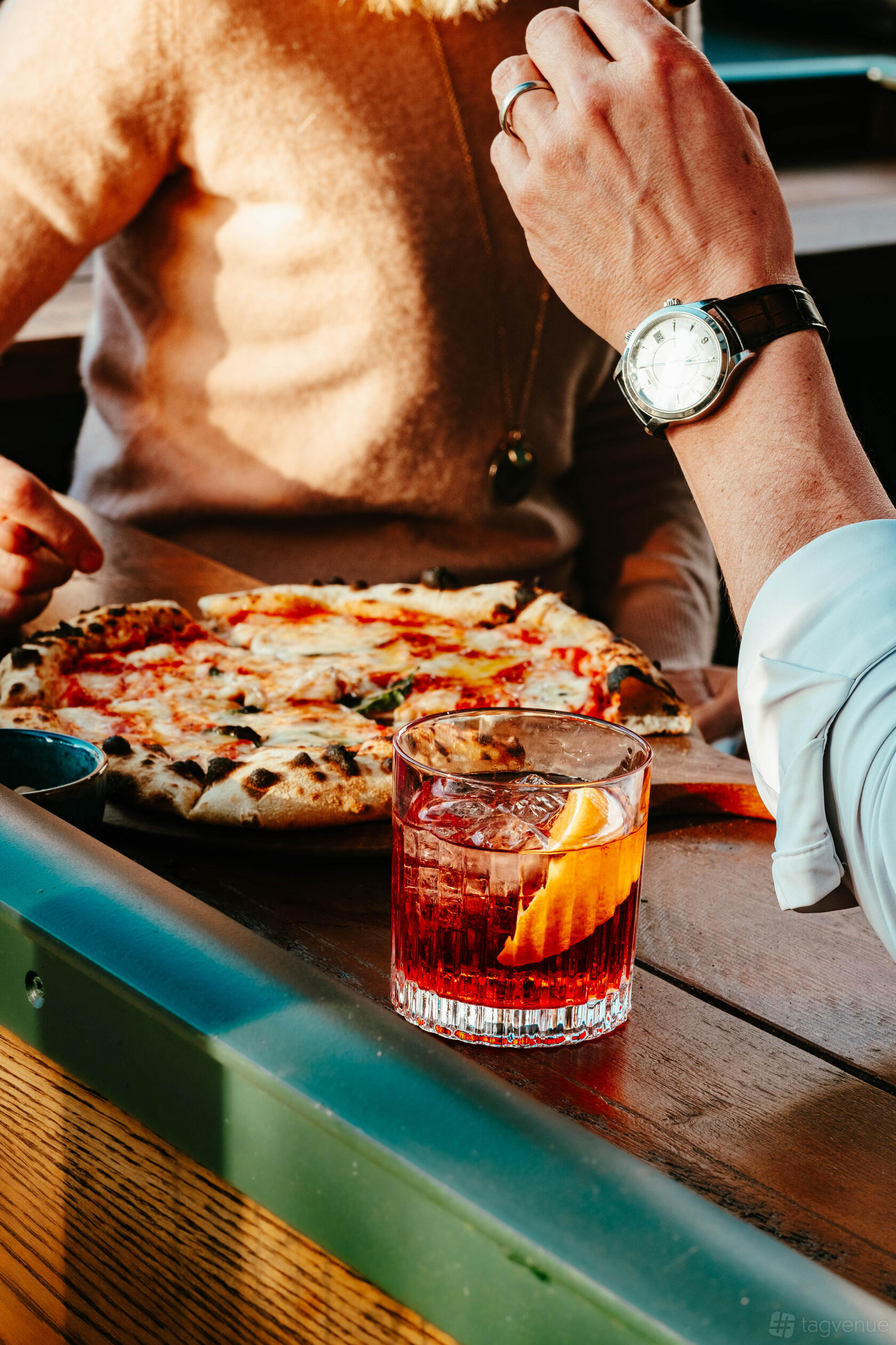 A cocktail bar event space with a wood-fired pizza and a Negroni cocktail with orange garnish at LOCKES Bar Covent Garden.