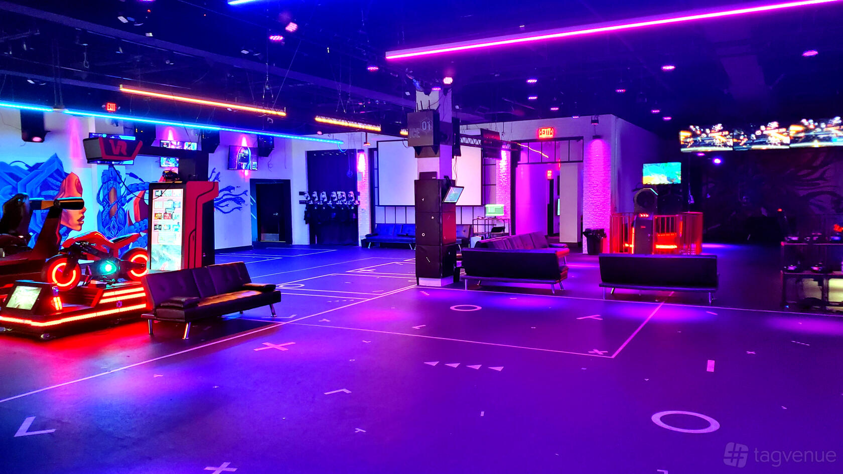 An event venue with neon lighting, virtual reality gaming booths, and lounge seating at Battleground VR.
