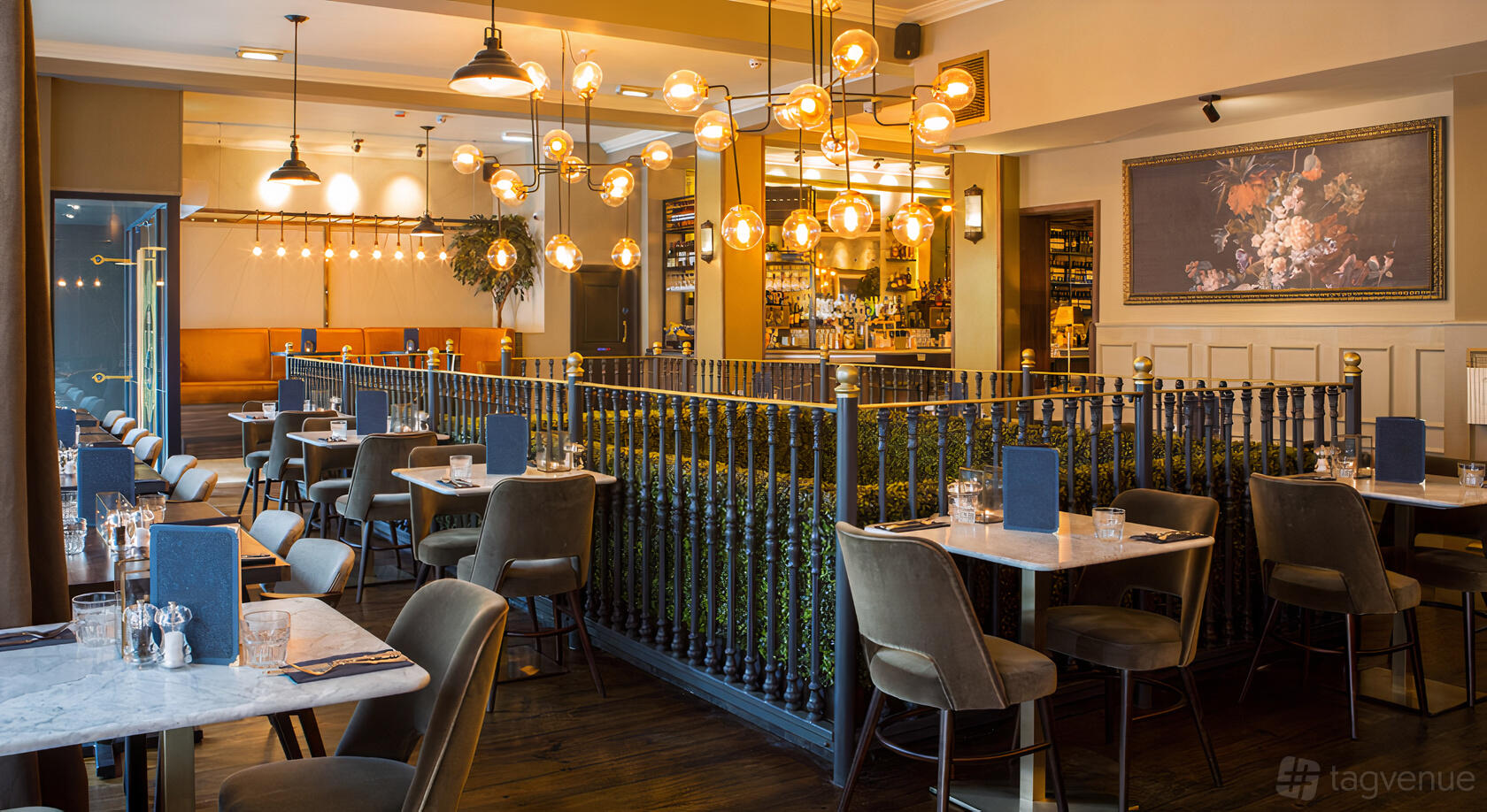 A bar with globe pendant lights, marble-topped tables, and plush chairs at The Lost and Found Greek Street.