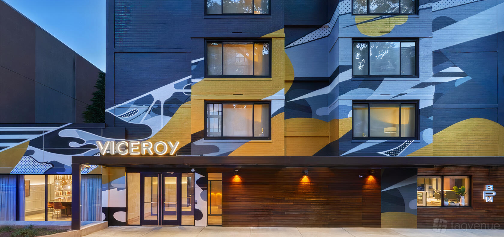 A hotel with a bold geometric mural and illuminated signage at the entrance of Viceroy Washington.