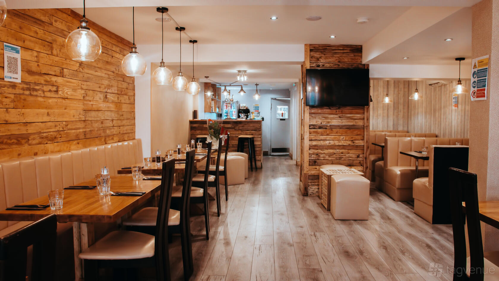 A restaurant with wooden panel walls, pendant lighting, and brown leather banquette seating at Smokin' Grill Steakhouse Kenley.