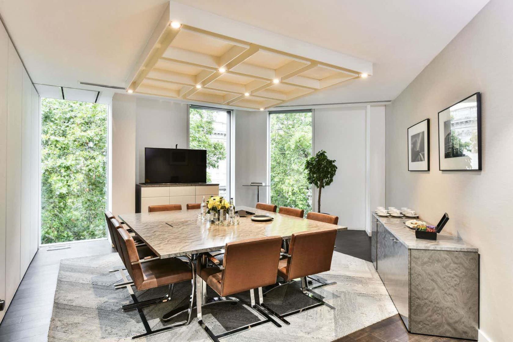 A meeting room with a marble conference table, brown leather chairs, and large windows at Octagon Point St Paul's.