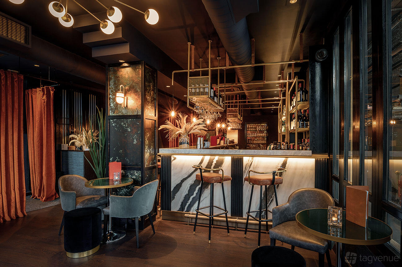 A restaurant with a marble-topped bar, velvet chairs, round tables, and pendant lighting at Gaucho Hampstead.