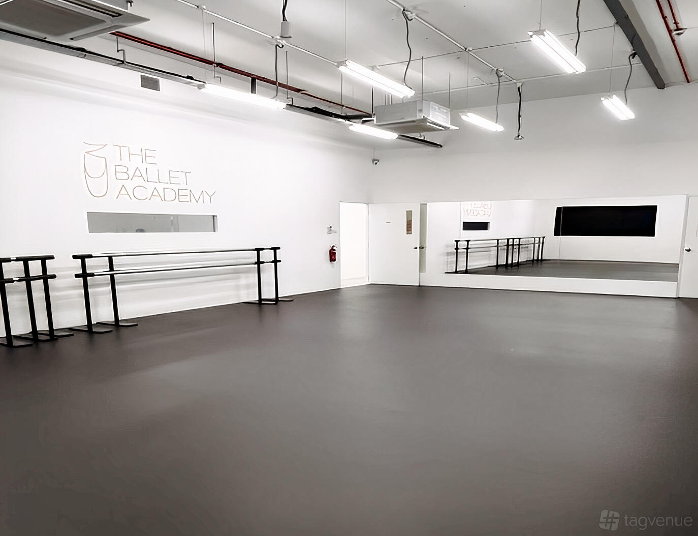 A dance studio with wall mirrors, ballet barres, and bright white walls at The Ballet Academy at SAFRA TOA PAYOH BRANCH.