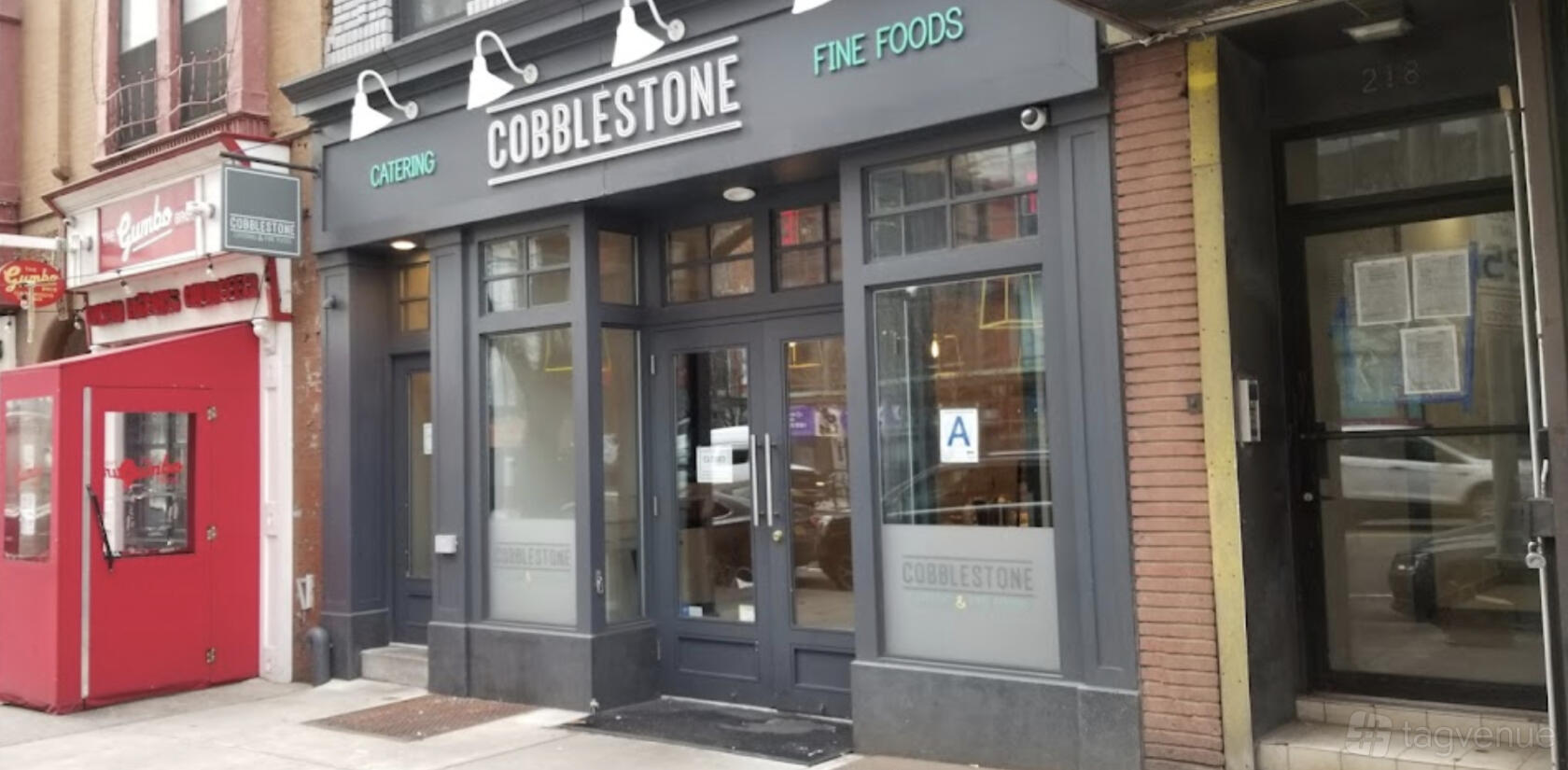 A versatile event space with a modern glass storefront and bold signage at Cobblestone Catering & Fine Foods.